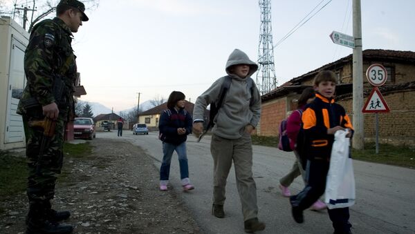 Um soldado romeno da força pacificadora da ONU guarda a passagem de crianças sérvias que vão à escola no enclave sérvio no Kosovo de Gorazdevac, em 2007 (foto de arquivo) - Sputnik Brasil