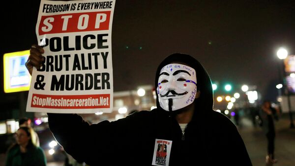 A protestor wearing a Guy Fawkes mask holds a sign as demonstrators march through the streets of Ferguson, Missouri, March 12, 2015 - Sputnik Brasil