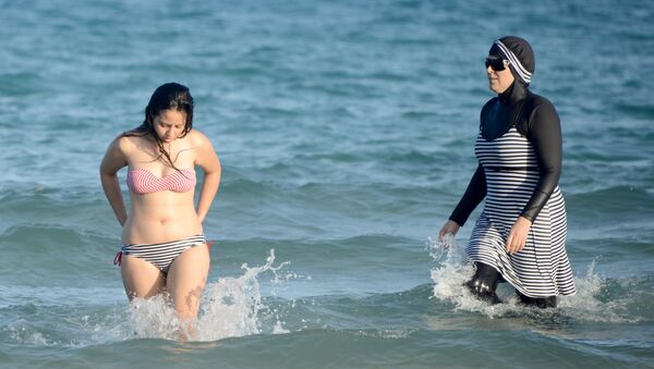 Uma mulher em burquíni se diverte no mar junto com uma mulher em maiô comum, em 16 de agosto de 2016, em uma praia perto de Tunis, na Tunísia - Sputnik Brasil