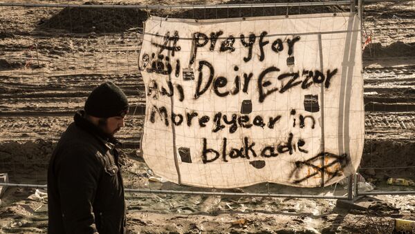 Uma pessoa passa em Calais, França, perto de um cartaz dizendo, em inglês: Ore por Deir ez-Zor, mais de 1 ano sob sítio - Sputnik Brasil