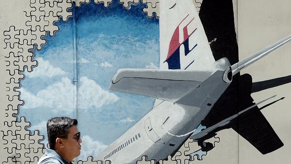 Homem passeia perante a muralha com a imagem do avião desaparecido Boeing 777 da Malaysia Airlines, Shah Alam, Malásia, março de 2016 - Sputnik Brasil