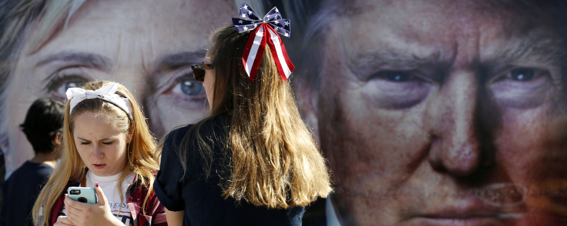 Pessoas aguardam ao lado de um ônibus adornado com fotos dos então candidatos à presidência dos EUA, Hillary Clinton e Donald Trump, em 2016 - Sputnik Brasil, 1920, 12.01.2023