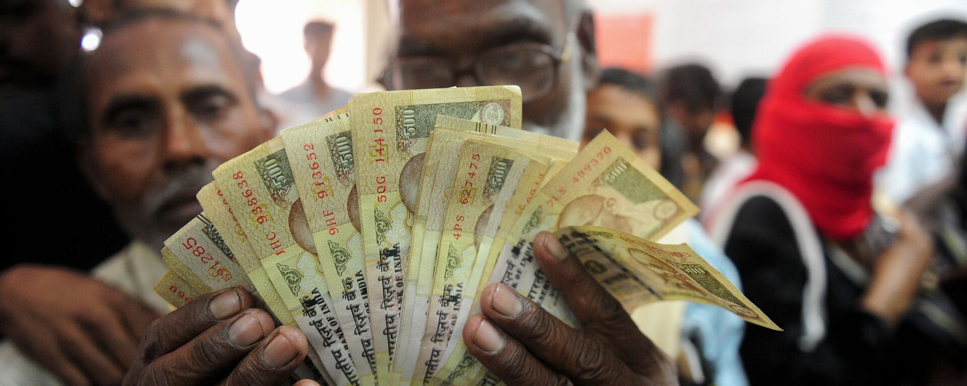 Um homem indiano segura nas mãos várias notas de 500 rupias, que perderam seu valor nominal após uma reforma do governo de Narendra Modi - Sputnik Brasil, 1920, 22.08.2022