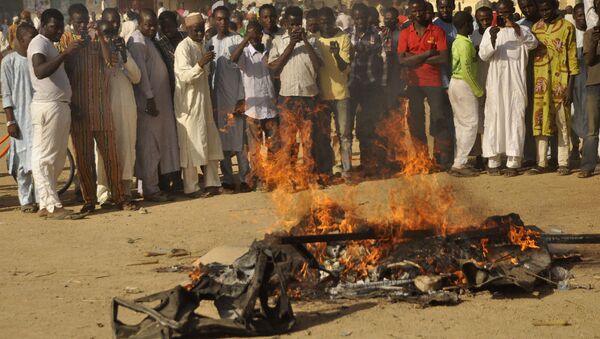 Multidão acompanha um pedaço de carro em chamas após uma explosão em 28 de novembro de 2014 em Kano, Nigéria; o local tinha sido alvejado pelo Boko Haram - Sputnik Brasil