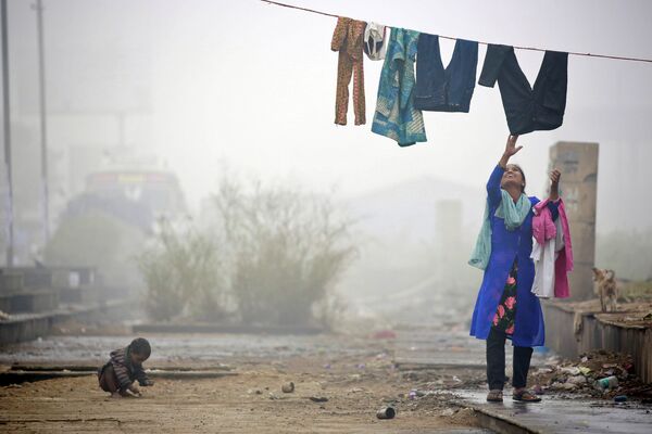 Mulher recolhe roupa durante nevoeiro forte em Nova Delhi, Índia - Sputnik Brasil