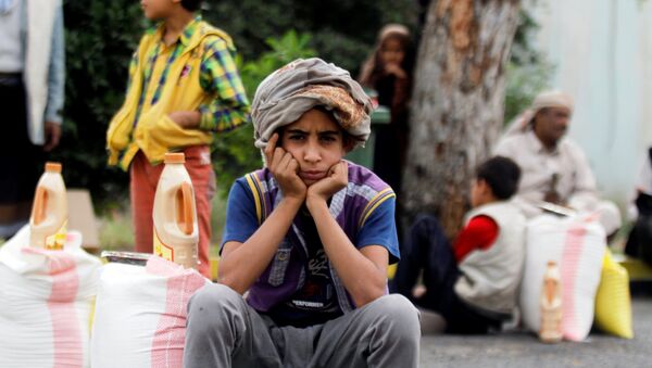 Um menino está sentando ao lado do alimento que ele recebeu de uma caridade local em Sanaa, Iêmen, junho 23, 2016 - Sputnik Brasil