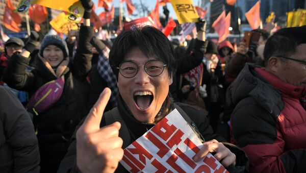 Um manifestante reage após o impeachment bem sucedido do parlamento sul-coreano da presidente Park Geun-hye enquanto multidões se juntam fora da Assembleia Nacional em Seoul em 9 de dezembro de 2016. - Sputnik Brasil