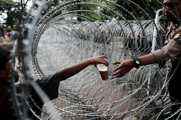 Policial indonésio compra bebida através do arame farpado - Sputnik Brasil