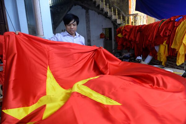 Trabalhador da oficina vietnamita segura bandeira nacional na véspera do Ano-novo chinês. - Sputnik Brasil
