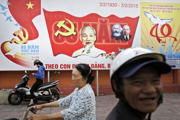 Habitantes da cidade andam de motos com outdoor do Partido Comunista do Vietnã ao fundo, retratando o herói nacional Ho Chi Mihn. - Sputnik Brasil