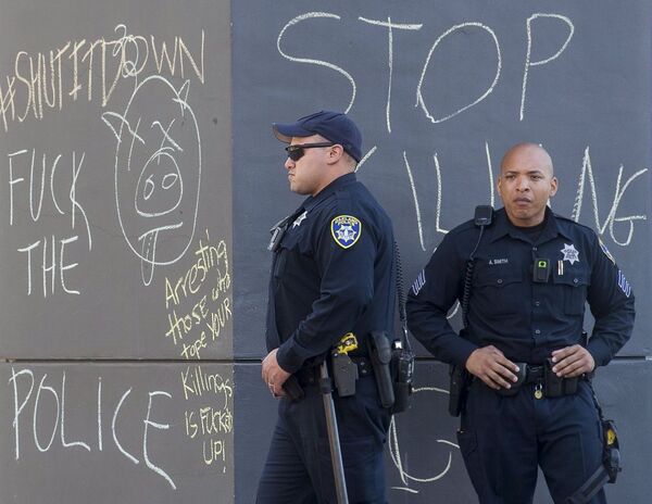 Oficiais de polícia perto de grafittis contra eles, em Oakland - Sputnik Brasil