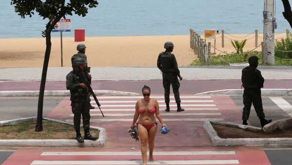 Uma mulher cruza uma via pública, guardada por soldados das Forças Armadas em Vitória, ES, em 8 de fevereiro - Sputnik Brasil