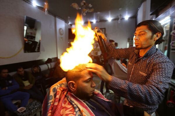 Barbeiro palestino Ramadan Odwan corta e arruma cabelo de um freguês usando fogo no seu salão situado na Faixa de Gaza. - Sputnik Brasil