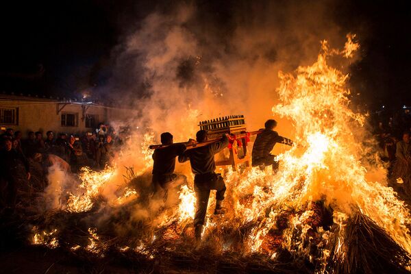 Homens carregando um andor funerário pulam por cima do fogo, o que garante boa sorte na celebração tradicional do Ano Novo chinês. - Sputnik Brasil