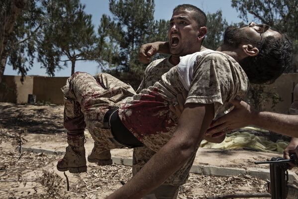 Foto de Alessio Romenzi mostra um combatente das forças líbias leais ao governo de Trípoli carregando seu camarada gravemente ferido por uma armadilha colocada pelos militantes do Daesh, na Líbia - Sputnik Brasil
