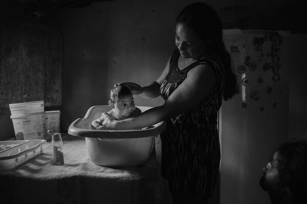 Imagem da série Vítimas do Zika, do fotógrafo Lalo de Almeida, mostra a brasileira Adriana Cordeiro Soares dando banho ao seu filho João Miguel, com 3 meses de idade, nascido com microcefalia causada pelo vírus do Zika - Sputnik Brasil