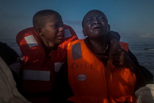 Foto Deixado Sozinho, tirada por Santi Palacios, retrata uma menina nigeriana de 11 anos (à esquerda), que falou sobre a morte de sua mãe na Líbia, sentada ao lado do seu irmão (à direita) dentro de um barco de resgate - Sputnik Brasil