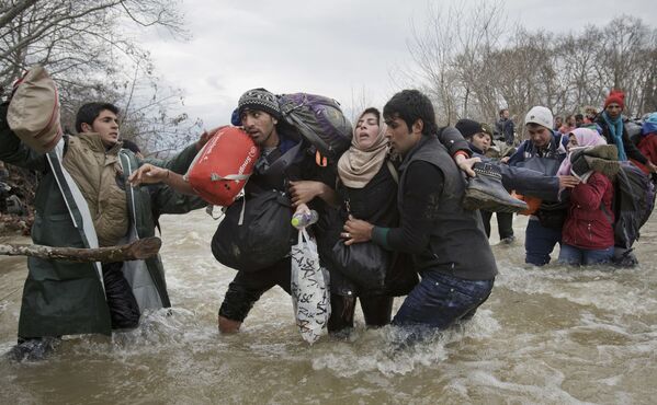 Imagem batizada como Passada de Migrantes, de Vadim Ghirda, retrata uma mulher apoiada por dois homens atravessando um rio em tentativa de atingir a Macedônia - Sputnik Brasil