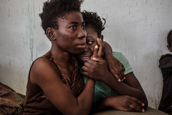 Foto denominada como Armadilha Migratória Líbia retrata dois refugiados nigerianos chorando e se abraçando no centro de detenção para refugiados conhecido por acusações de assalto sexual e violência, em Surman, na Líbia - Sputnik Brasil