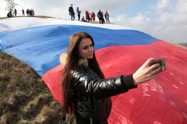 Menina tira selfie com enorme bandeira da Rússia durante festival em Simferopol - Sputnik Brasil