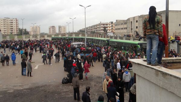 Combatentes da oposição e suas famílias se reúnem, enquanto se preparam para subir a um ônibus, antes da evacuação do bairro rebelde de Waer, na cidade de Homs, em 18 de março de 2017 - Sputnik Brasil