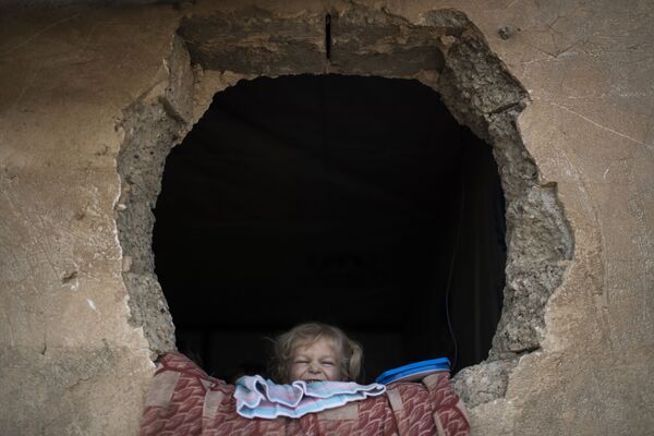 Criança olha para a fora da janela no leste de Mossul - Sputnik Brasil
