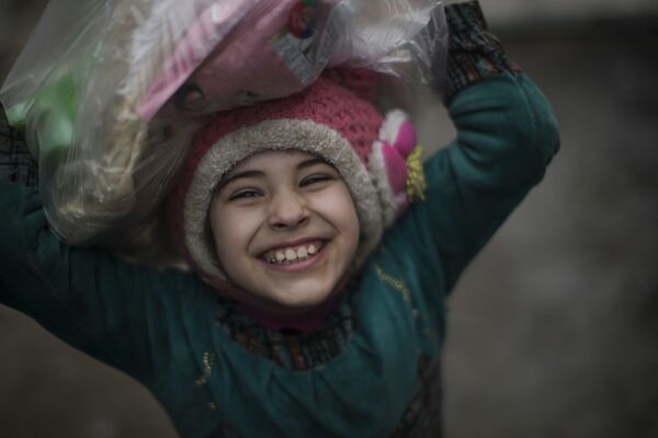 Criança iraquiana sorri após receber recursos alimentares das forças de segurança do Iraque perto da linha da frente, durante o combate contra o Daesh em Mossul ocidental, Iraque, março de 2017. - Sputnik Brasil