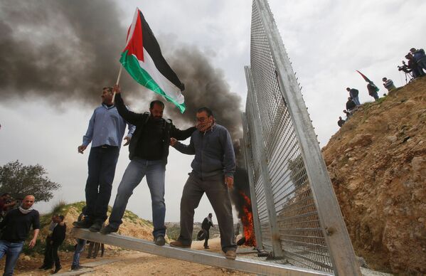 Palestinos tentam remover parte da cerca israelense durante um protesto na Cisjordânia, em 30 de março - Sputnik Brasil