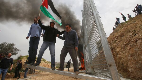 Palestinos tentam remover parte da cerca israelense durante um protesto na Cisjordânia, em 30 de março - Sputnik Brasil