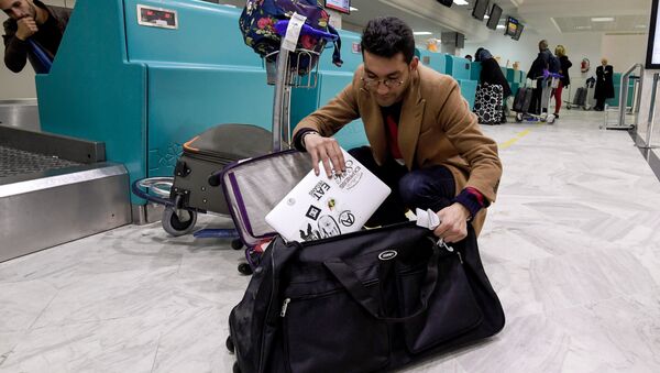 A Libyan traveller packs his laptop in his suitcase before boarding his flight for London at Tunis-Carthage International Airport on March 25, 2017 - Sputnik Brasil
