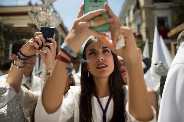 Moça tira fotografias da procissão durante a Semana Santa em Sevilha - Sputnik Brasil
