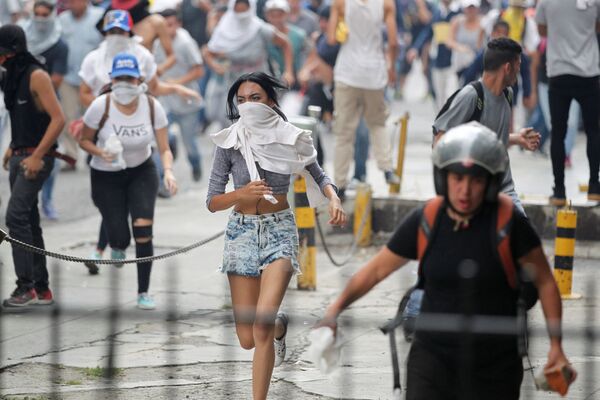 Manifestantes fogem da polícia durante os protestos contra o presidente venezuelano Nicolás Maduro em Caracas. - Sputnik Brasil