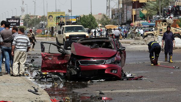 Civis e forças de segurança em volta de um carro que explodiu em Talibiya, no leste de Bagdá - Sputnik Brasil