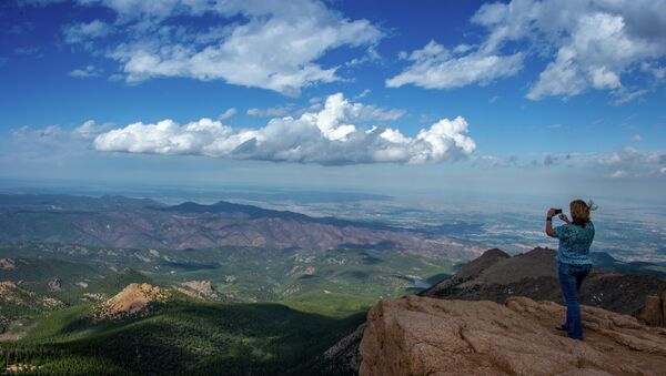 A woman takes a picture at the top of Pikes Peak mountain in the Front Range of the Rocky Mountains within Pike National Forest, 10 miles (16 km) west of Colorado Springs, Colorado, on June 08,2013 - Sputnik Brasil