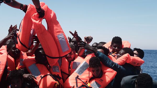 Migrants in an overcrowded plastic raft reach out for life jackets during a search and rescue operation by rescue ship Aquarius, operated by SOS Mediterranean and Doctors without Borders, in central Mediterranean Sea May 18, 2017 - Sputnik Brasil