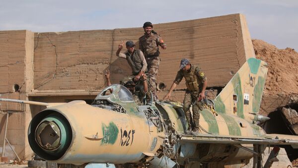 Combatentes das Forças Democráticas da Síria (FDS) posando com um avião destruído no aeroporto militar de Tabqa após o terem reconquistado ao Daesh, em 9 de abril de 2017 - Sputnik Brasil