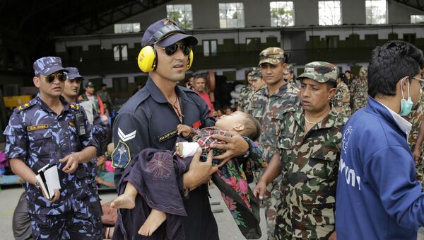 Um militar da Força Aérea da Índia socorre uma criança no Nepal. - Sputnik Brasil