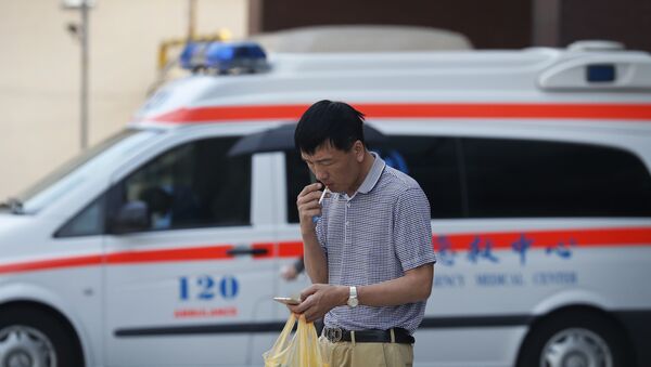 Um homem fuma um cigarro na frente de um carro de ambulância em Pequim em 31 de maio de 2017 - Sputnik Brasil