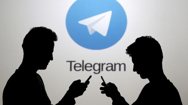 Dois homens, usando seus smartphones, estão em frente ao logotipo do Telegram - Sputnik Brasil
