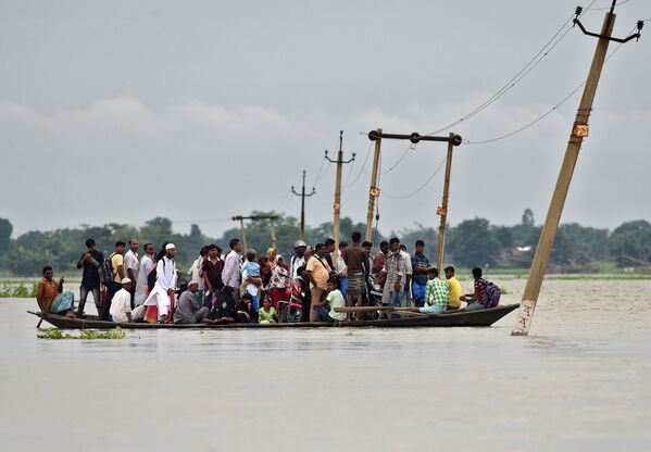 Moradores da povoação de Asigarh atravessam caminho inundado no estado de Assam, Índia - Sputnik Brasil