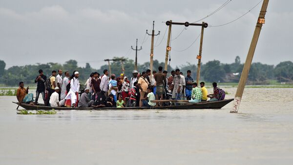 Moradores da povoação de Asigarh atravessam caminho inundado no estado de Assam, Índia - Sputnik Brasil