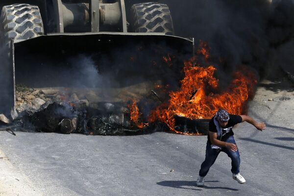 Um manifestante palestino foge de um buldózer do exército israelense durante os confrontos na aldeia de Kobar, a oeste de Ramalá - Sputnik Brasil