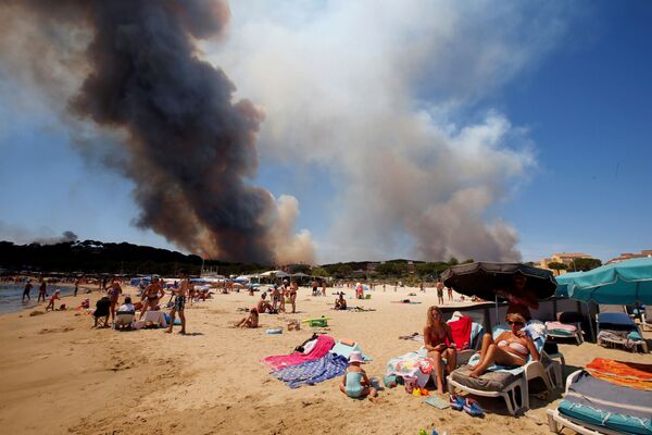 Fumaça produzida pelos incêndios florestais paira por cima das praias francesas enquanto os turistas desfrutam do sol no local Bormes-les-Mimosas - Sputnik Brasil