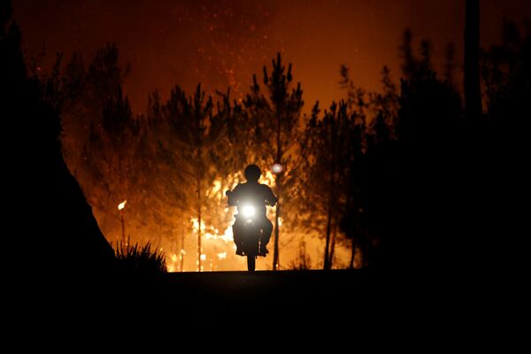 Um bombeiro anda de moto em direção oposta ao incêndio florestal na aldeia de Mação, perto de Castelo Branco, em Portugal - Sputnik Brasil