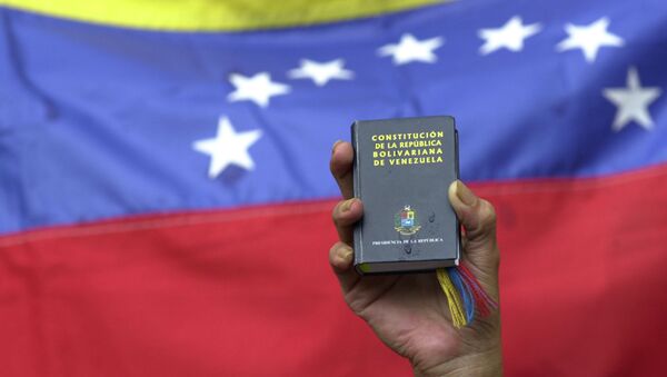 Um manifestante segurauma cópia em miniatura da constituição da Venezuela em frente à bandeira da nação durante uma manifestação do governo em Caracas, Venezuela, terça-feira, 13 de abril de 2004 (foto de arquivo). - Sputnik Brasil