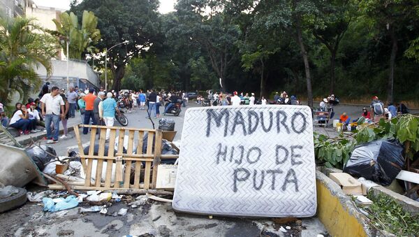 As pessoas passam por uma barricada de rua que inclui um colchão com as palavras Maduro filho da puta durante confrontos nas eleições da Assembleia Constituinte realizadas em Caracas, Venezuela, 30 de julho de 2017. - Sputnik Brasil