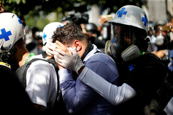 Um manifestante ferido é ajudado por membros voluntários de uma equipe de resposta de atenção primária, enquanto se reúne contra o governo do presidente da Venezuela, Nicolas Maduro, em Caracas - Sputnik Brasil