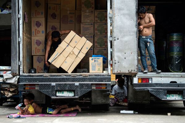 Crianças descansam debaixo de um caminhão que está sendo descarregado na cidade filipina de Manila - Sputnik Brasil