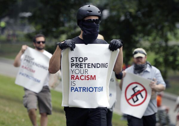 Manifestante com placa dizendo pare de fingir que seu racismo é patriotismo - Sputnik Brasil