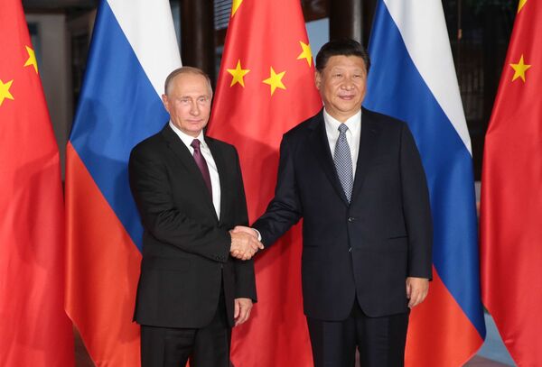 O líder russo, Vladimir Putin, e o líder chinês, Xi Jinping, apertam as mãos durante encontro no palco da nona cúpula do BRICS - Sputnik Brasil